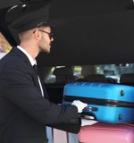 Young driver loading suitcases into car trunk outdoors