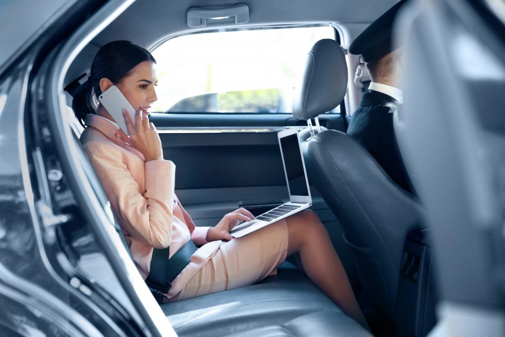 Businesswoman speaking by cellphone and riding a car